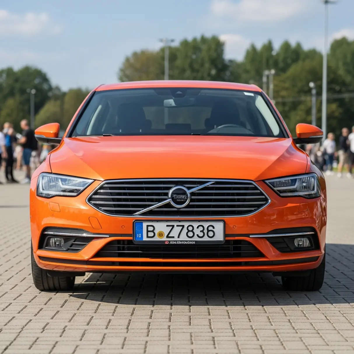 Pomarańczowy samochód marki polestar z przodu, na parkingu, z ludźmi w tle.