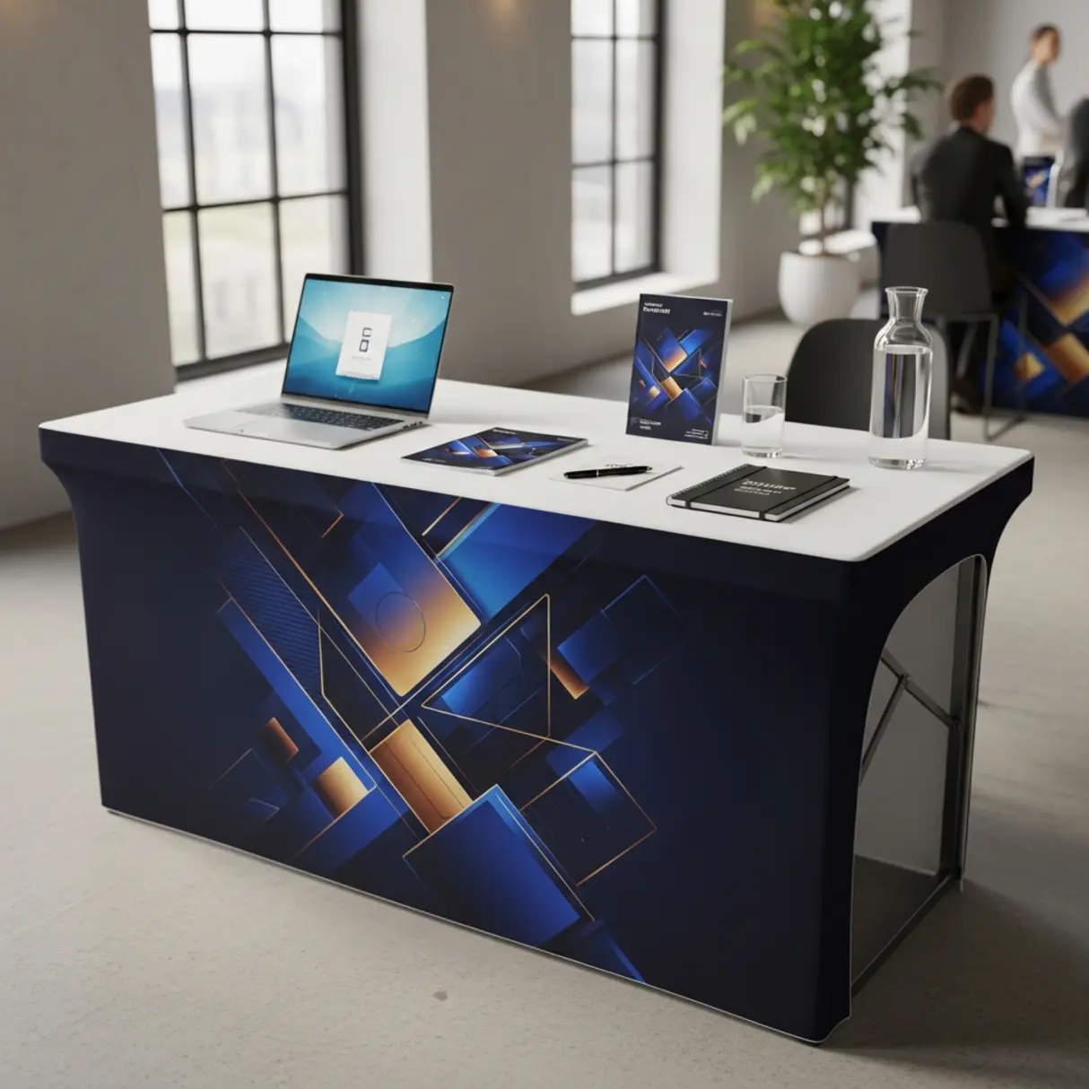 Stół eventowy z naciągniętym obrusem z grafiką, laptopem i materiałami promocyjnymi.